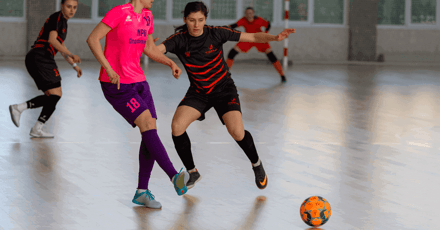Futsal players play a game of futsal indoors