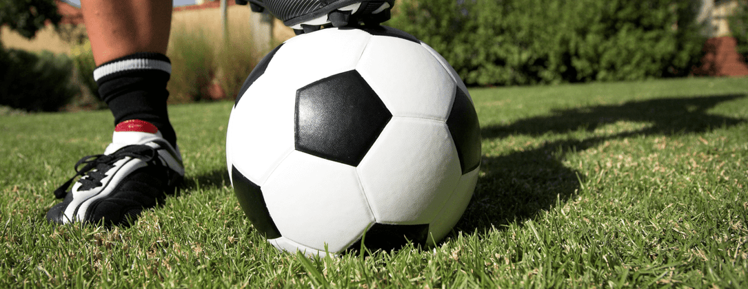 Mans foot on soccer ball on grass in backyard