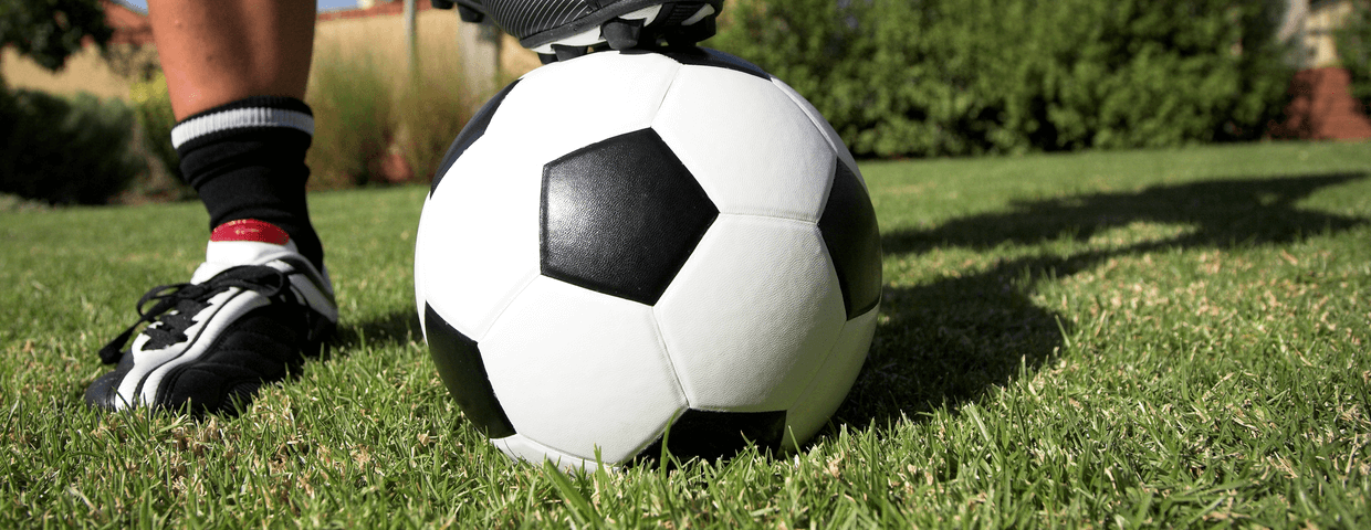 Mans foot on soccer ball on grass in backyard